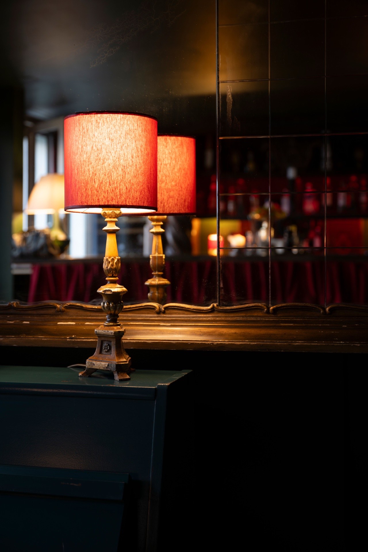 Red lamps reflected in an antique mirror behind the bar at Le Bar