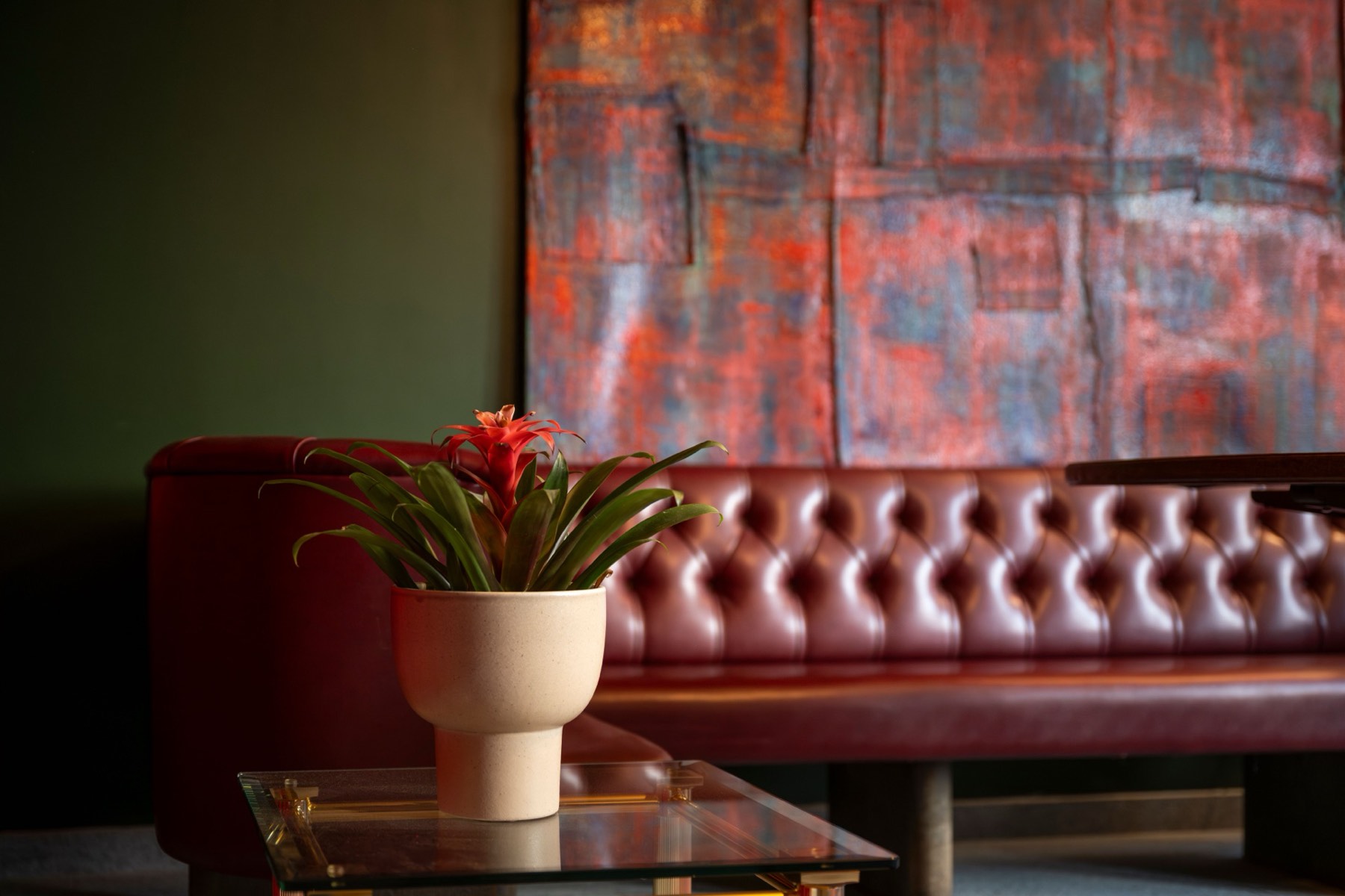 Bromeliad flower on tufted red leather with textile art behind, at Le Bar