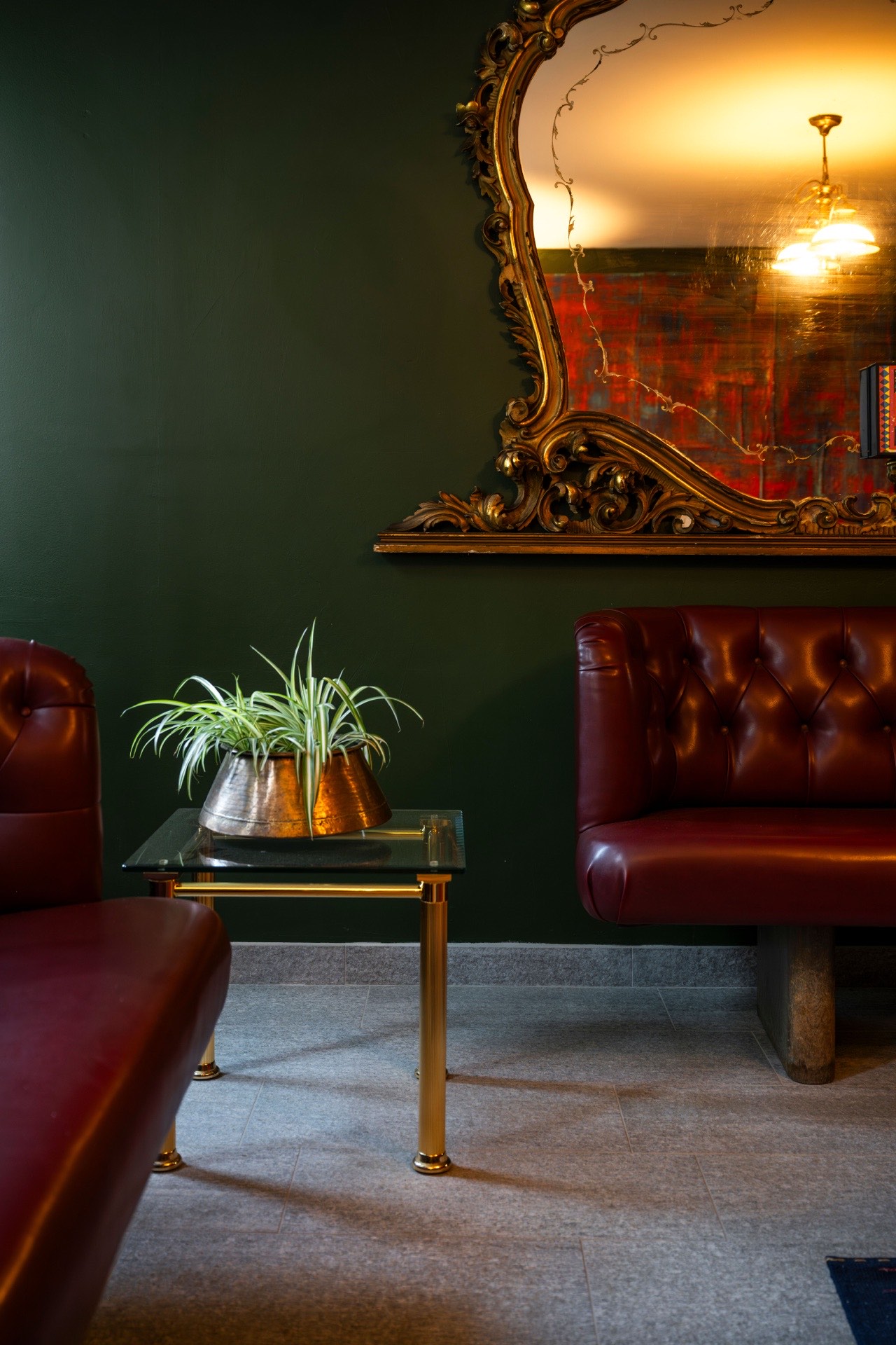 A gilded baroque mirror above a red leather banquette at Le Bar
