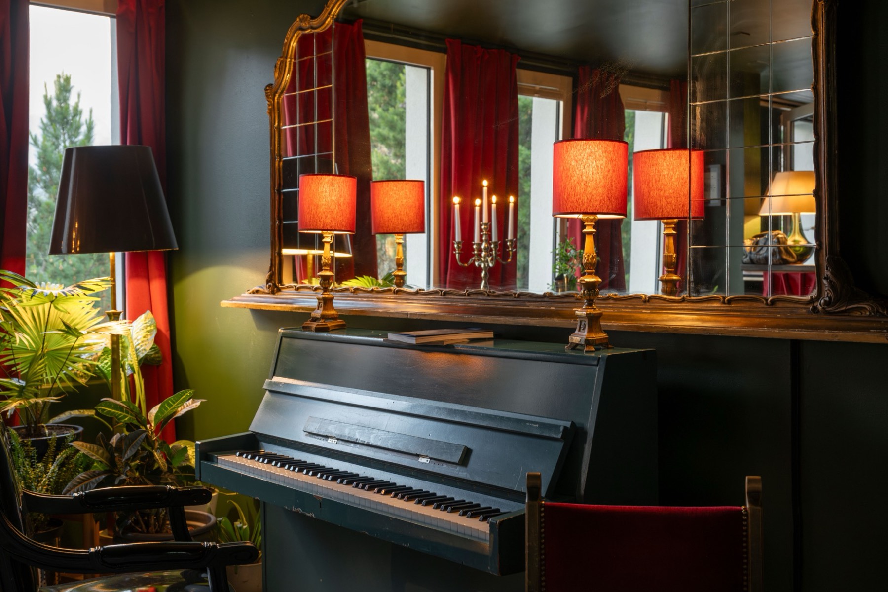 The piano corner at Le Bar with red lamps and baroque mirrors