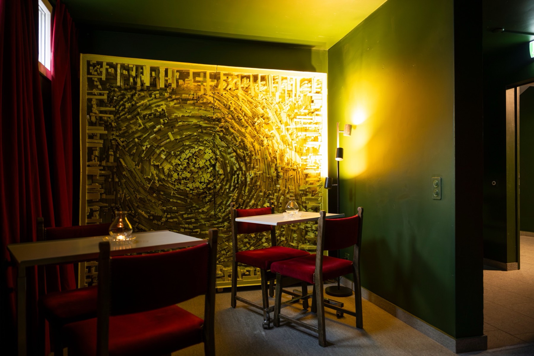 The smaller room at Le Bar — two tables beneath the golden spiral relief